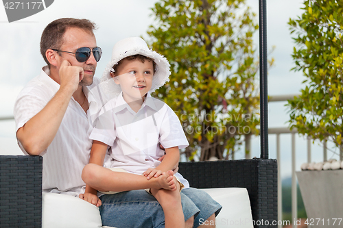 Image of Father and son relaxing near a swimming pool  at the day time.