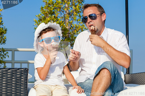 Image of Father and son relaxing near a swimming pool  at the day time.