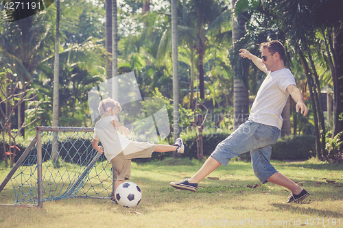 Image of Father and son playing in the park  at the day time.