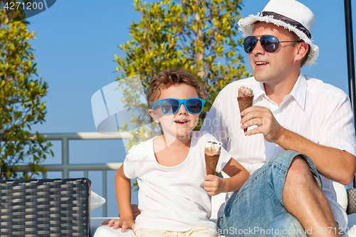 Image of Father and son relaxing near a swimming pool  at the day time.