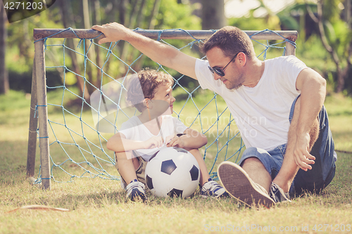 Image of Father and son playing in the park  at the day time.