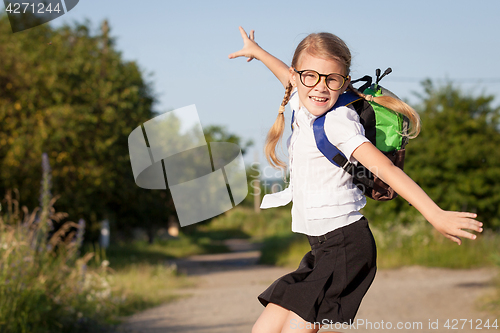 Image of Smiling young school girl in a school uniform jumping on the roa