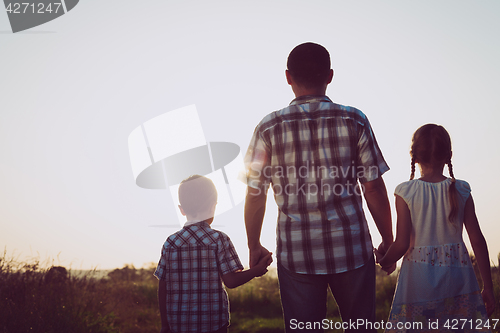 Image of Father and children playing in the park at the sunset time.