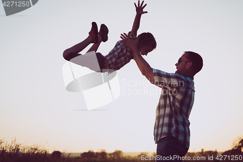 Image of Father and son playing in the park at the sunset time.