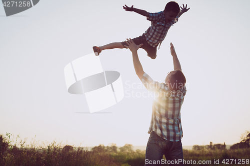 Image of Father and son playing in the park at the sunset time.