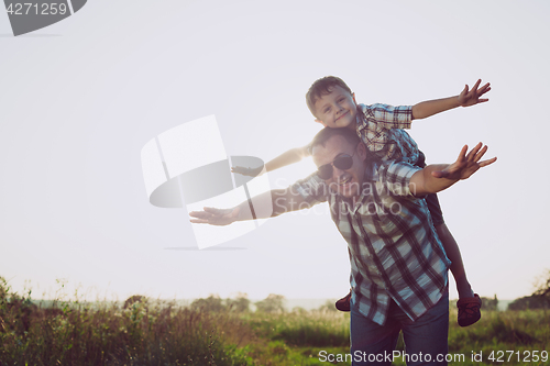 Image of Father and son playing in the park at the sunset time.