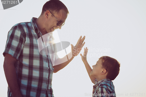 Image of Father and son playing in the park at the sunset time.