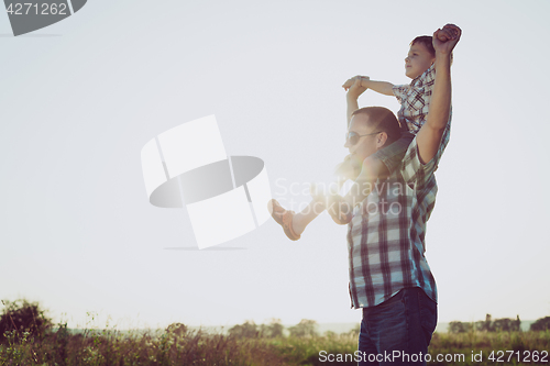 Image of Father and son playing in the park at the sunset time.