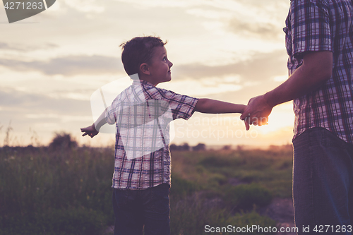 Image of Father and son playing in the park at the sunset time.