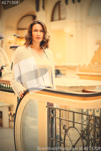 Image of woman in a light knitted coat near an escalator