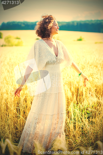 Image of happy smiling middle-aged woman spinning in a white dress in a f