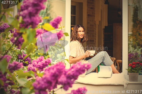 Image of Beautiful smiling middle-aged woman with a tea cup and a book