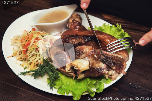 Image of Man eats tasty dish of pork shank