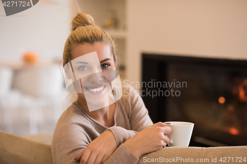 Image of woman with a mug near a fireplace