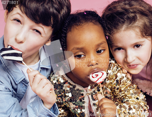 Image of lifestyle people concept: diverse nation children playing together, caucasian boy with african little girl holding candy happy smiling 