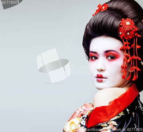 Image of young pretty geisha in black kimono among sakura, asian ethno cl
