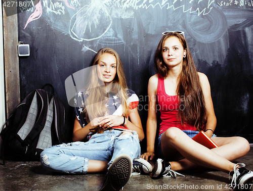 Image of back to school after summer vacations, two teen real girls in classroom with blackboard painted together, lifestyle people concept