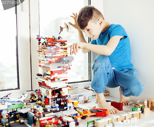 Image of little cute preschooler boy playing lego toys at home happy smil