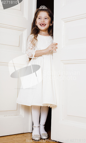 Image of little cute girl at home, opening door well-dressed in white dress, adorable milk fairy teeth, curious child