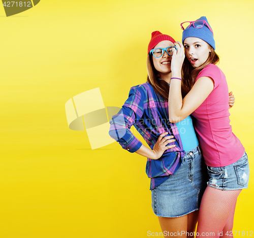 Image of lifestyle people concept: two pretty young school teenage girls having fun happy smiling on yellow background