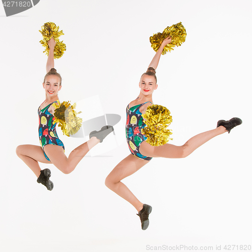 Image of The two of teen cheerleaders jumping at white studio