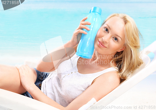 Image of Woman with bottle of water on beach 