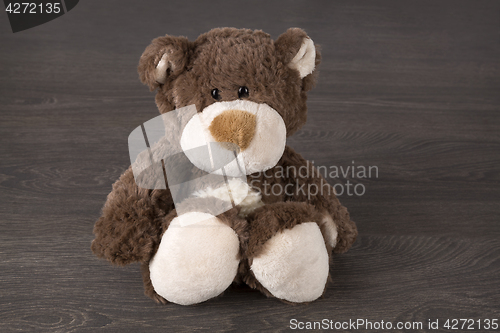 Image of Brown teddy bear sitting on wooden background