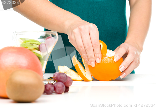 Image of Cook is peeling orange for fruit dessert