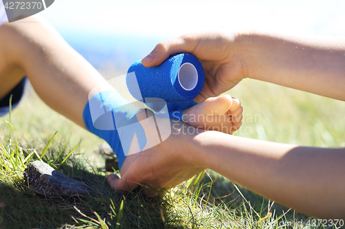 Image of An accident on a mountain trail. First aid, twisted leg.