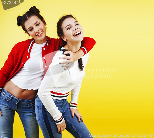 Image of lifestyle people concept: two pretty young school teenage girls having fun happy smiling on yellow background