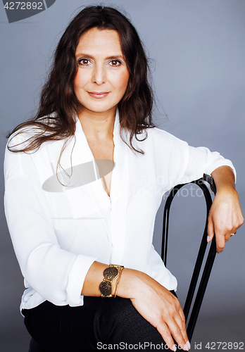 Image of pretty brunette confident mature woman sitting on chair in studi