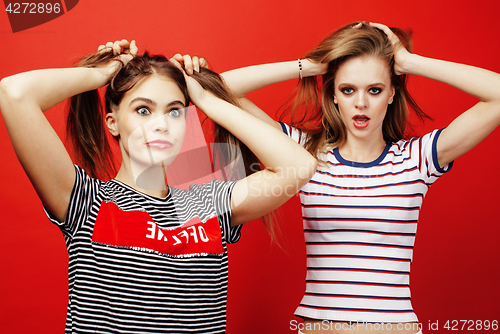 Image of two best friends teenage girls together having fun, posing emotional on red background, besties happy smiling, lifestyle people concept 