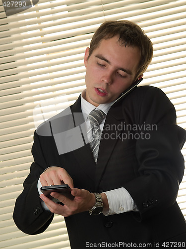 Image of Businessman with calculator talking phone