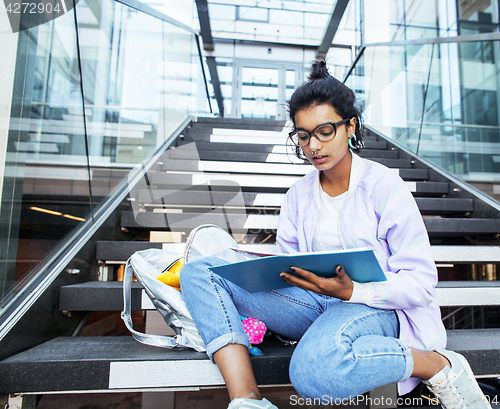Image of young cute indian girl at university building sitting on stairs 