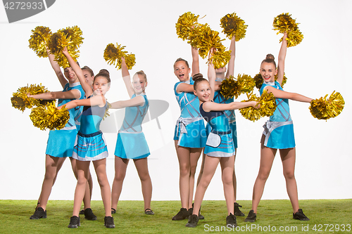 Image of The group of teen cheerleaders posing at white studio