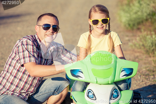 Image of Father and daughter playing on the road at the day time.