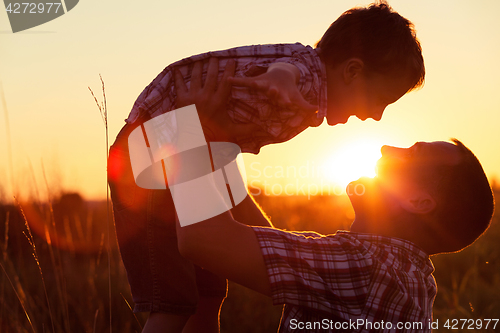 Image of Father and son playing at the park at the sunset time.