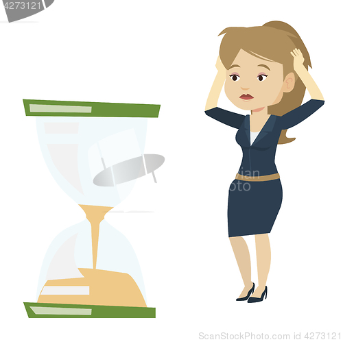 Image of Desperate business woman looking at hourglass.