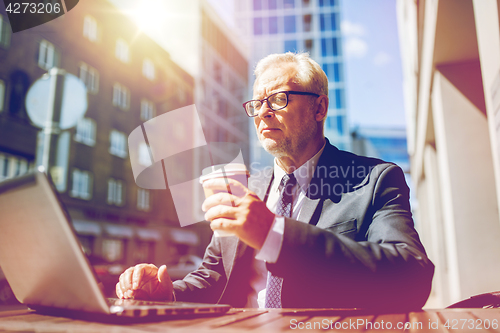 Image of senior businessman with laptop drinking coffee