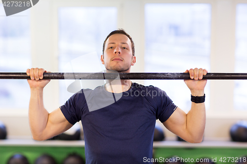 Image of man exercising on bar and doing pull-ups in gym