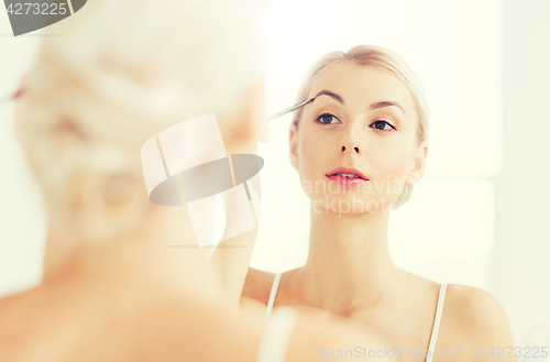 Image of woman with brush doing eyebrow makeup at bathroom