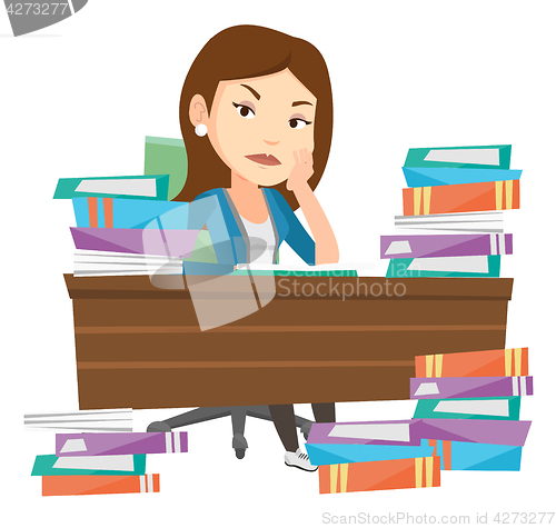 Image of Student sitting at the table with piles of books.