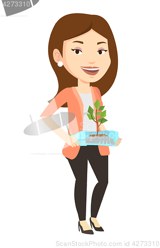 Image of Woman holding plant growing in plastic bottle.