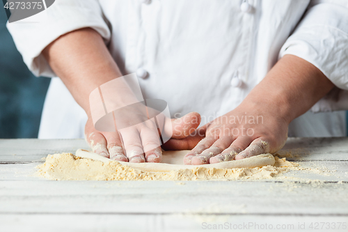 Image of Closeup hand of chef baker in white uniform making pizza at kitchen