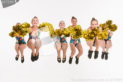 Image of The group of teen cheerleaders jumping at white studio