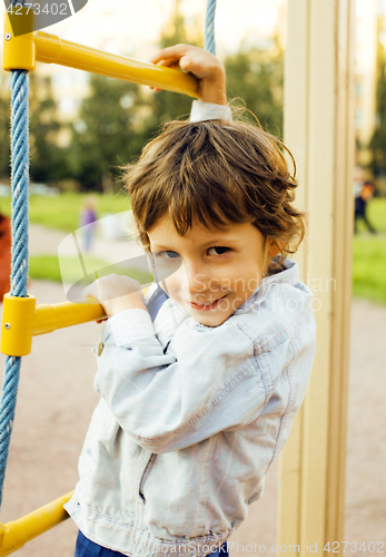 Image of little cute boy playing on playground, hanging on gymnastic ring