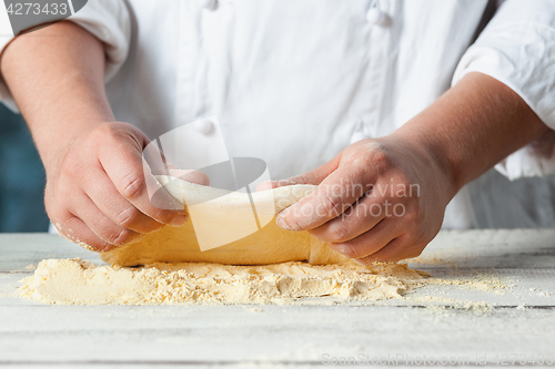 Image of Closeup hand of chef baker in white uniform making pizza at kitchen