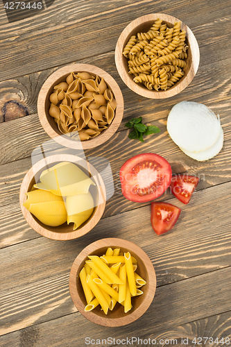 Image of Variety of Pasta Wooden Bowls Cutting Boards Tomato Onion