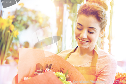 Image of smiling florist woman with bunch at flower shop