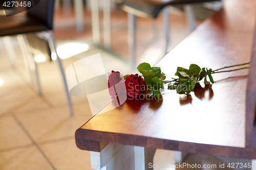 Image of red roses on bench at funeral in church